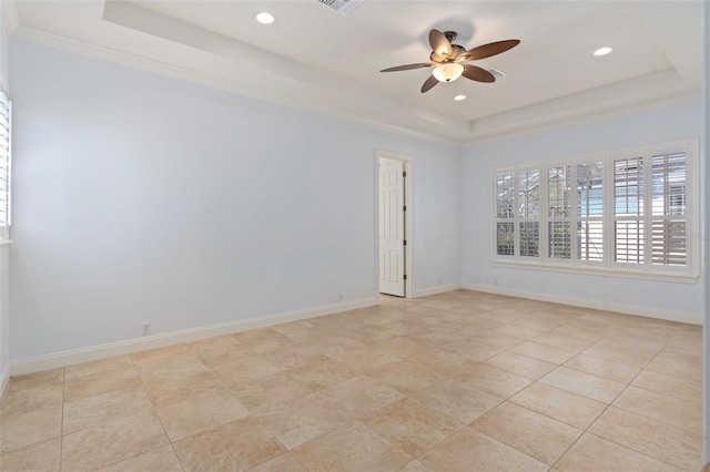 spare room featuring a tray ceiling, a ceiling fan, and baseboards