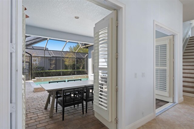 interior space featuring brick floor, a sunroom, a textured ceiling, and baseboards