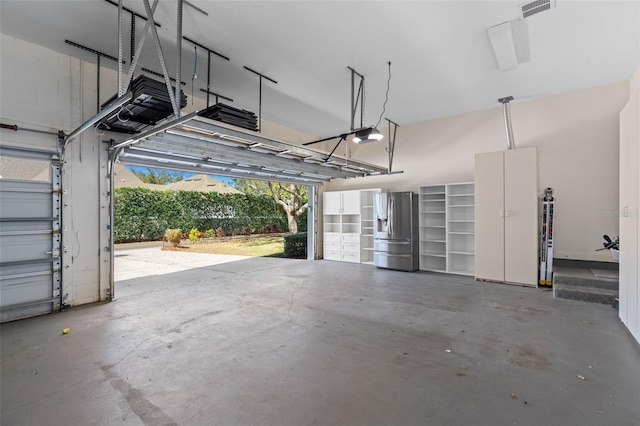 garage with a garage door opener, visible vents, and stainless steel fridge with ice dispenser