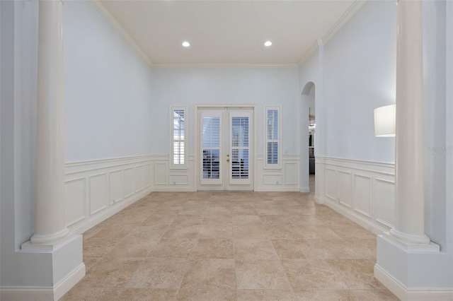 unfurnished room with arched walkways, french doors, decorative columns, and crown molding