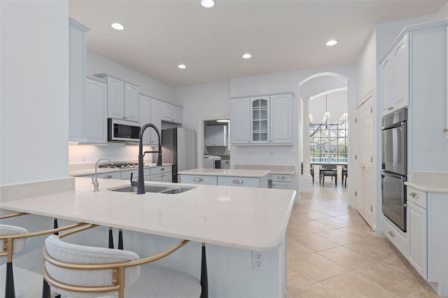 kitchen with light tile patterned floors, arched walkways, a breakfast bar, a center island, and recessed lighting