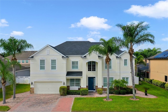 view of front of home featuring an attached garage, decorative driveway, a front yard, and stucco siding