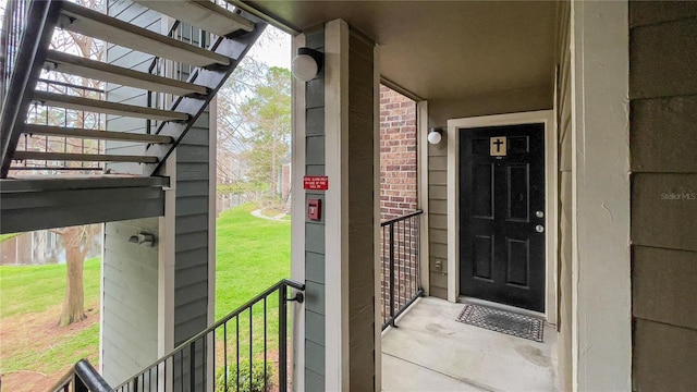 view of exterior entry featuring brick siding and a lawn