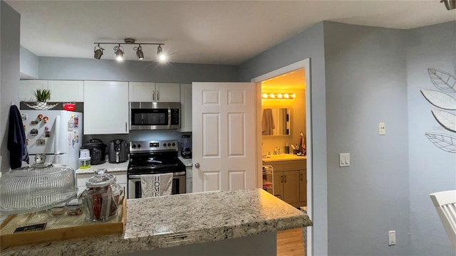 2200 Metropolitan Way Unit 926, Orlando, FL 32839 - kitchen featuring appliances with stainless steel finishes, a sink, white cabinets, light stone counters, and light wood-type flooring