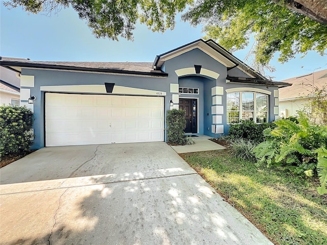 single story home with stucco siding, an attached garage, and concrete driveway