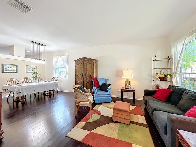 living room featuring dark wood finished floors, baseboards, visible vents, and a wealth of natural light