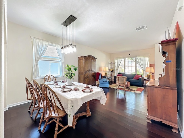 dining space with dark wood finished floors, a notable chandelier, baseboards, and visible vents