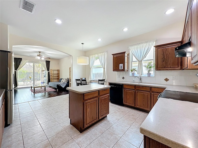 kitchen with visible vents, a sink, range hood, freestanding refrigerator, and dishwasher