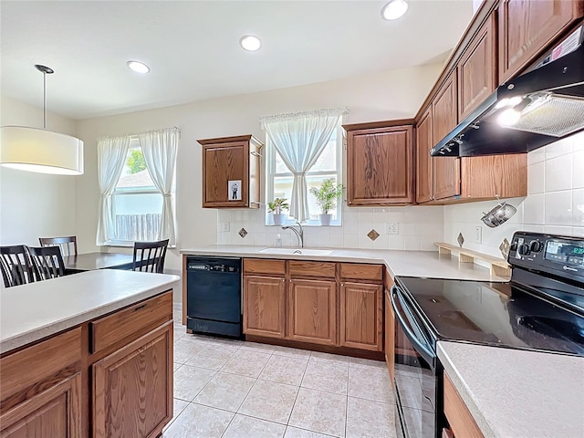 kitchen featuring under cabinet range hood, light countertops, decorative backsplash, black appliances, and a sink