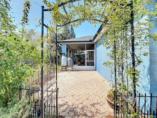 exterior space with fence, stucco siding, a patio, a sunroom, and a ceiling fan