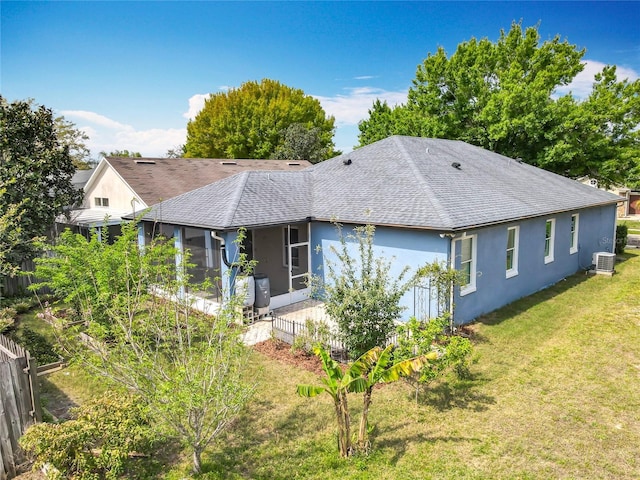 rear view of property featuring a yard, roof with shingles, central AC unit, and a sunroom