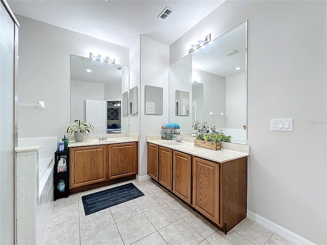 full bathroom with tile patterned floors, visible vents, a garden tub, two vanities, and a sink