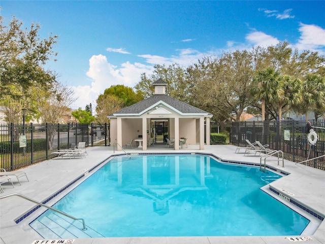 pool featuring a patio area, fence, and an outbuilding