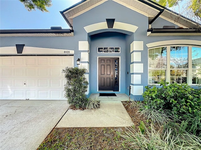 doorway to property featuring a garage, driveway, and stucco siding