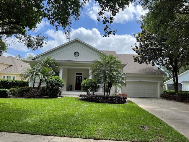 greek revival inspired property featuring a garage, driveway, a front lawn, and stucco siding