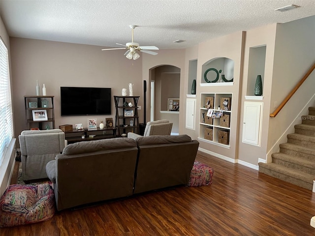 living area with visible vents, dark wood-style floors, stairway, a textured ceiling, and a healthy amount of sunlight