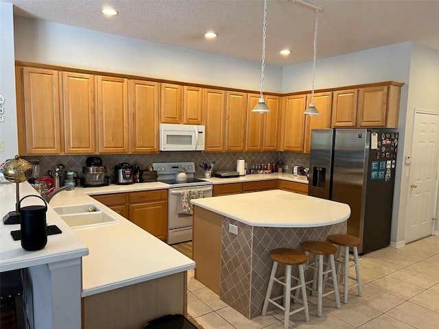 kitchen featuring a breakfast bar, white appliances, light countertops, and hanging light fixtures