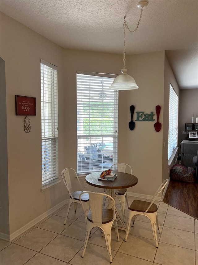 dining room featuring light tile patterned floors, a textured ceiling, and baseboards