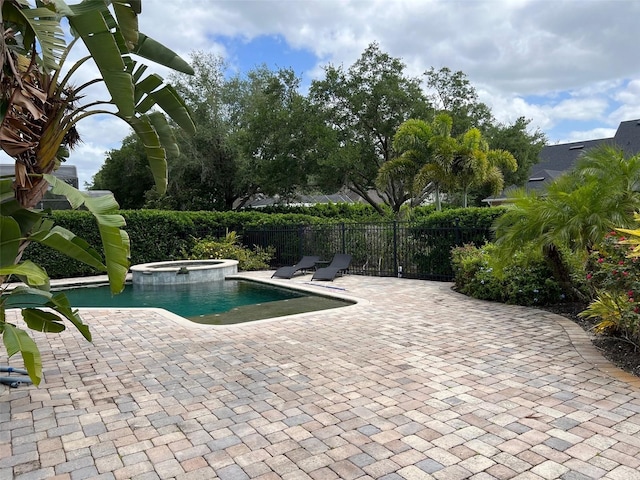 view of swimming pool featuring a patio area, fence, and a pool with connected hot tub