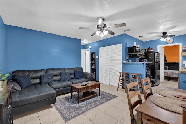 living room featuring light tile patterned floors, ceiling fan, and visible vents