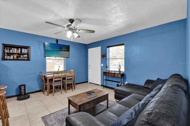 living room with light tile patterned flooring, a ceiling fan, and baseboards