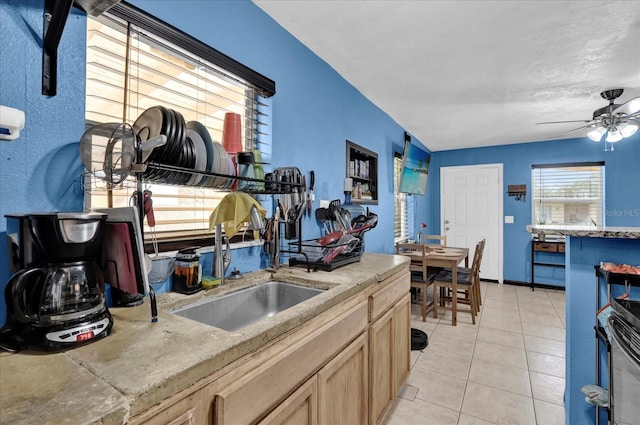 kitchen with light tile patterned floors, light countertops, light brown cabinetry, stainless steel range with electric stovetop, and a sink