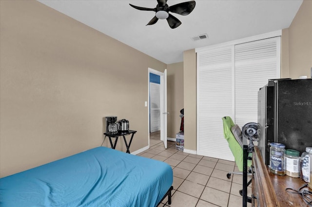 bedroom featuring light tile patterned floors, ceiling fan, visible vents, baseboards, and freestanding refrigerator