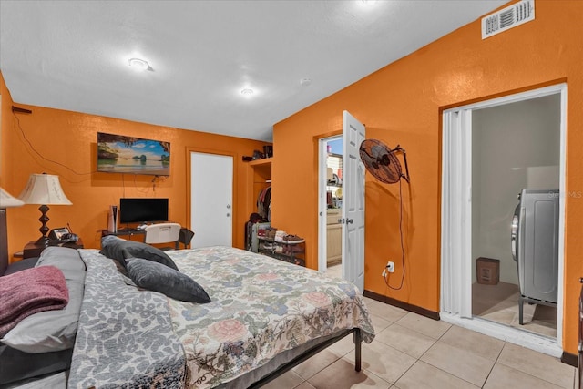 bedroom featuring vaulted ceiling, visible vents, washer / clothes dryer, and light tile patterned flooring