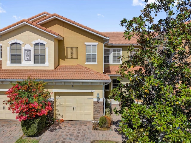 view of front of house featuring a garage, a tiled roof, decorative driveway, and stucco siding