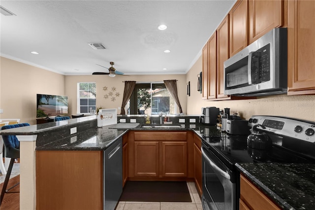 kitchen with stainless steel appliances, a peninsula, a sink, visible vents, and a kitchen breakfast bar