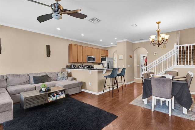 living room with arched walkways, dark wood-style flooring, visible vents, and crown molding