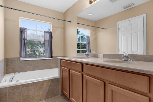 bathroom with tiled bath, a healthy amount of sunlight, visible vents, and a sink