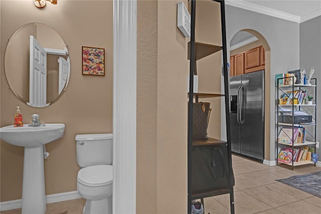 bathroom featuring tile patterned flooring, baseboards, crown molding, and toilet