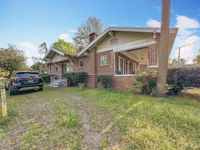 view of front of house featuring a chimney, a front yard, and brick siding