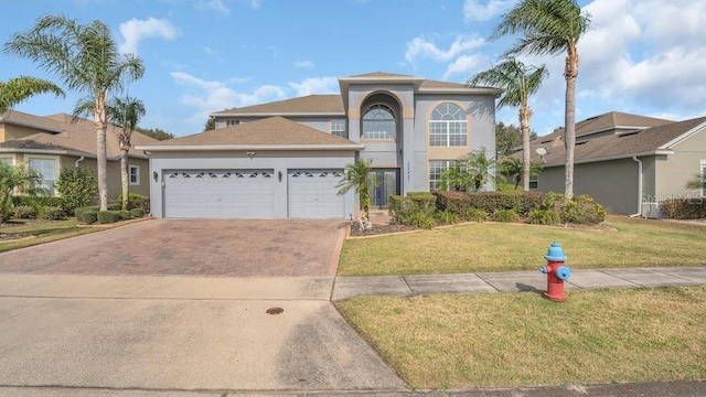 view of front of property featuring a garage, a front lawn, decorative driveway, and stucco siding