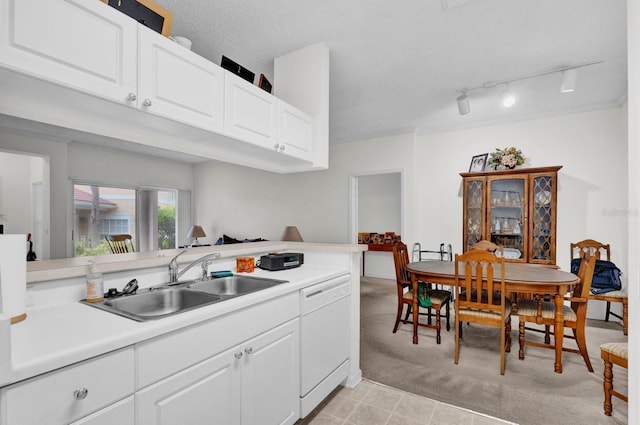 kitchen with light countertops, white cabinetry, white dishwasher, a sink, and a peninsula