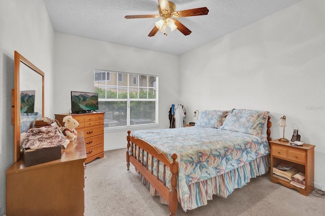 bedroom with a ceiling fan, a textured ceiling, and light colored carpet