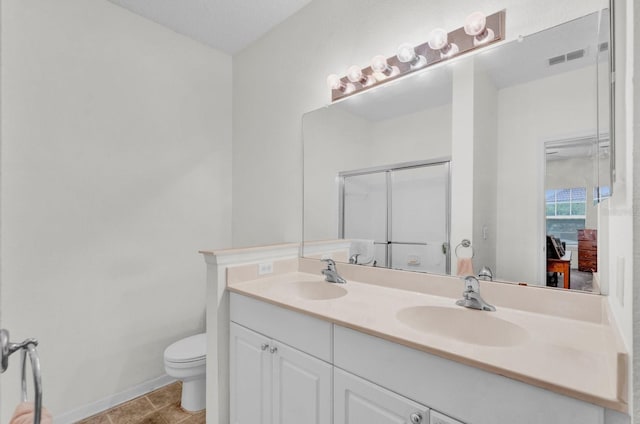 full bathroom featuring toilet, a shower with door, visible vents, and a sink