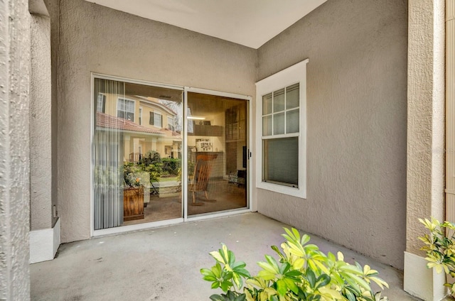 property entrance with a patio and stucco siding