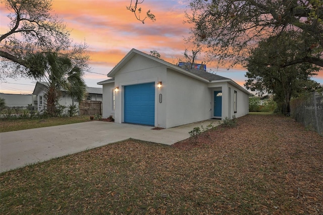 view of front of home featuring driveway, an attached garage, fence, and stucco siding