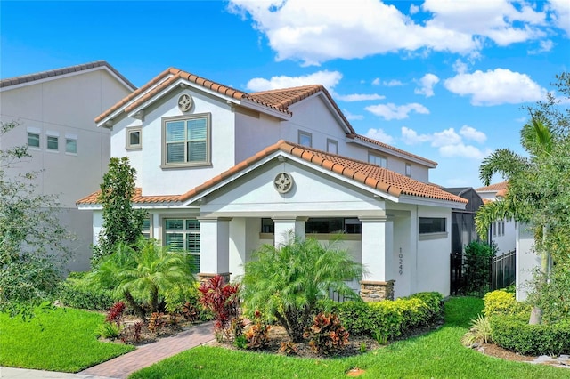 mediterranean / spanish-style home with a tile roof, fence, a front lawn, and stucco siding