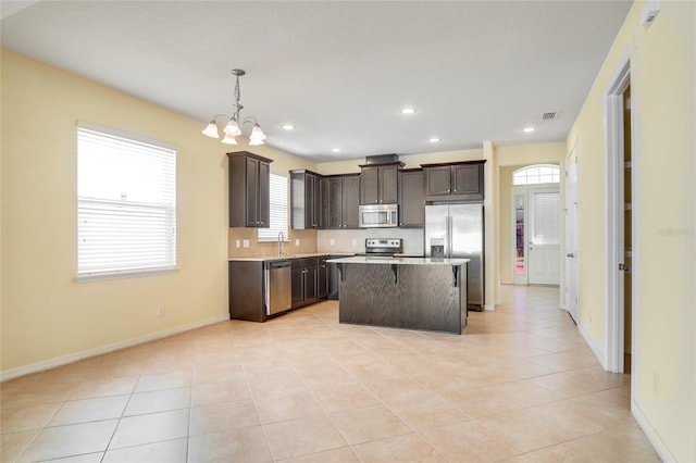 kitchen with decorative backsplash, a kitchen island, appliances with stainless steel finishes, light countertops, and dark brown cabinets