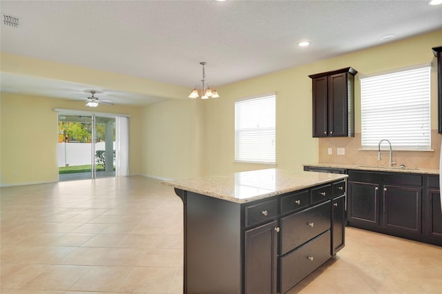 kitchen featuring light tile patterned floors, a sink, visible vents, open floor plan, and a center island