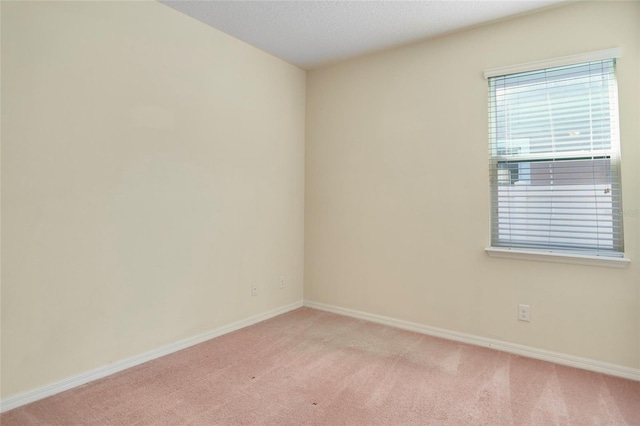 unfurnished room with baseboards, a textured ceiling, and light colored carpet