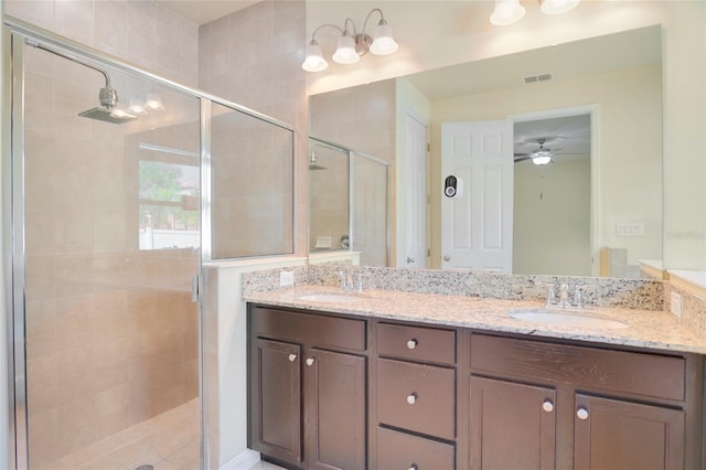 full bathroom with double vanity, a stall shower, visible vents, and a sink