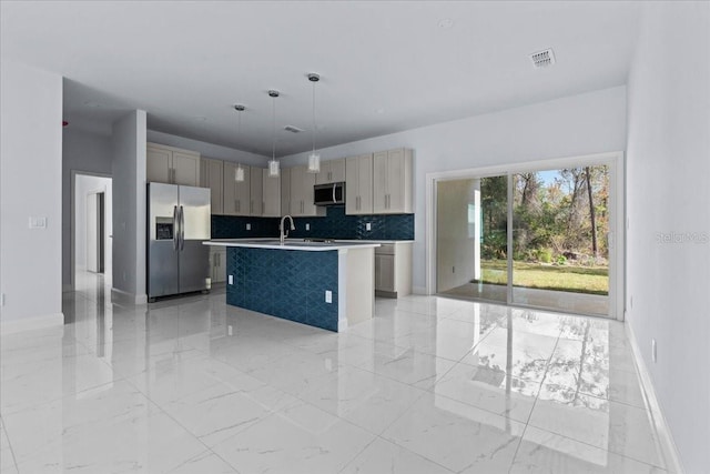 kitchen with an island with sink, marble finish floor, stainless steel appliances, light countertops, and pendant lighting