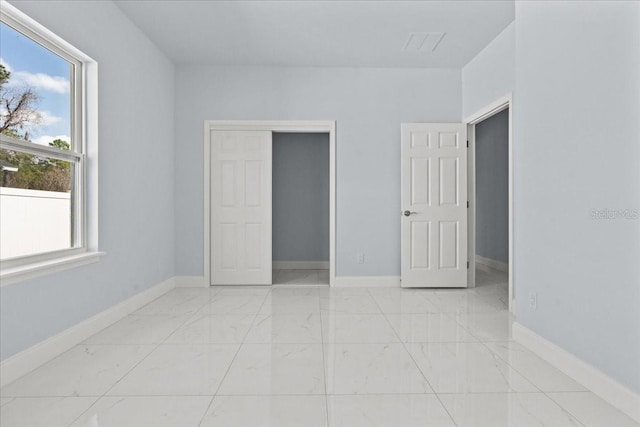 unfurnished bedroom featuring marble finish floor and baseboards