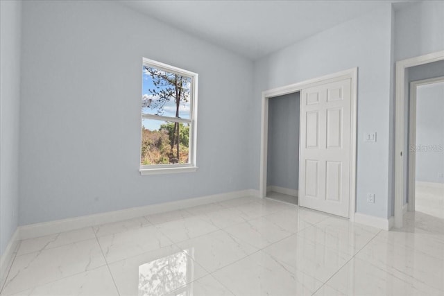 unfurnished bedroom with marble finish floor and baseboards