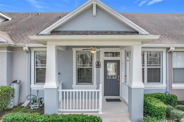 view of exterior entry featuring a shingled roof, covered porch, and stucco siding