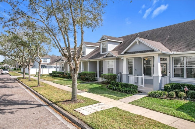 townhome / multi-family property with a front yard, covered porch, a residential view, and stucco siding